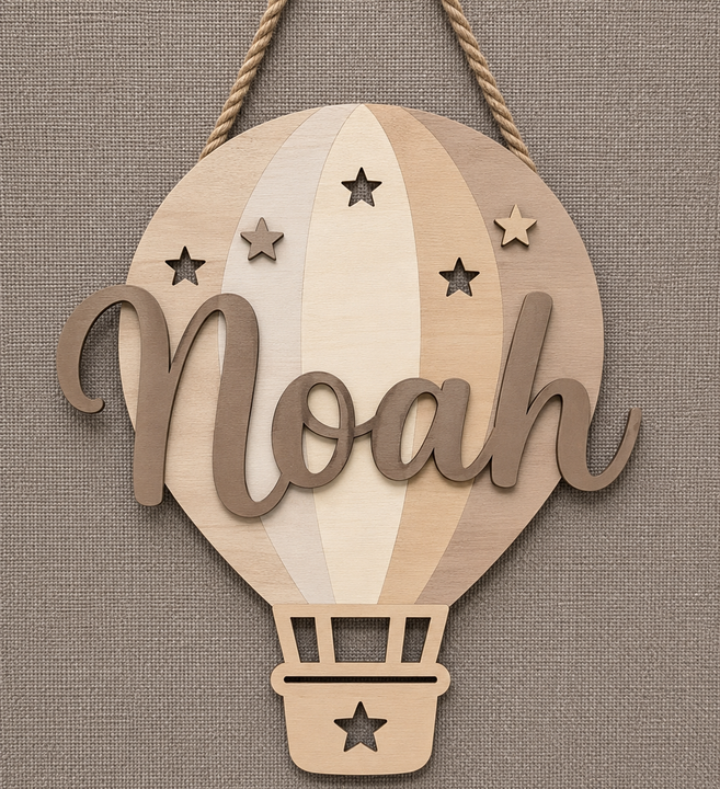 Personalized wooden hot air balloon wall hanging with the name 'Noah' in script, hanging against a textured linen background.